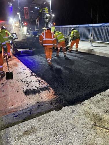 Road workers laying tarmac