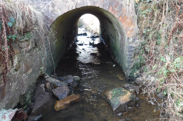 A small stream runs through a culvert under the north abutment