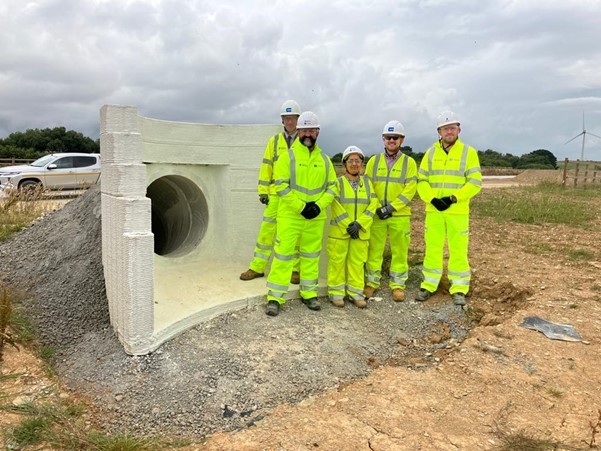 Picture showing National Highways and contractor staff standing next to the printed headwall in their hi-vis clothing