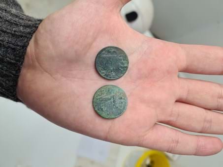 Two coins found in a burial, on a man's palm