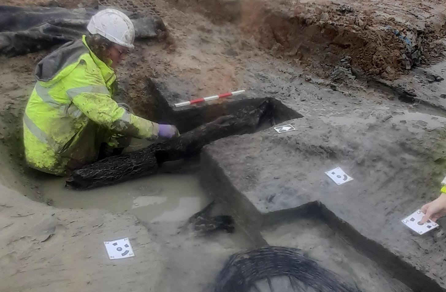 Archaeologist sat on the floor excavating wattle panel and small possible post