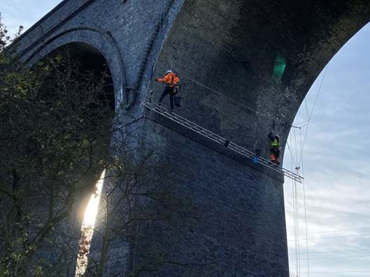 Construction workers under the arches, high up under structure of Crigglestone Viaduct.