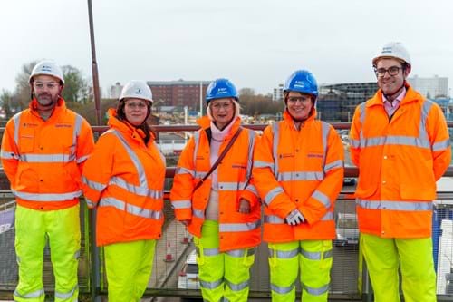 Group shot of Emma Hardy MP, Kathyrn Shillito and the A63 project team in hi-vis gear, on a bridge overlooking the A63 construction site