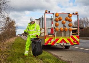 Person in hi-vis clothing picking litter from motorway verge