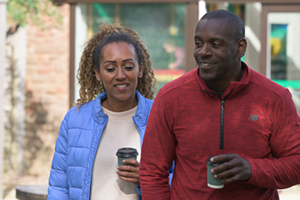 a couple walking with their hot drinks