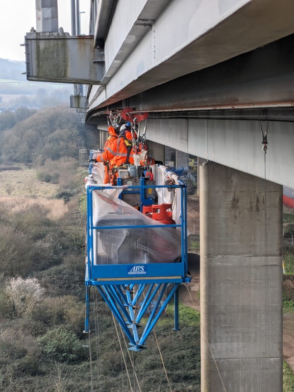 Inspection work taking place on a runway beam under the bridge parapets.