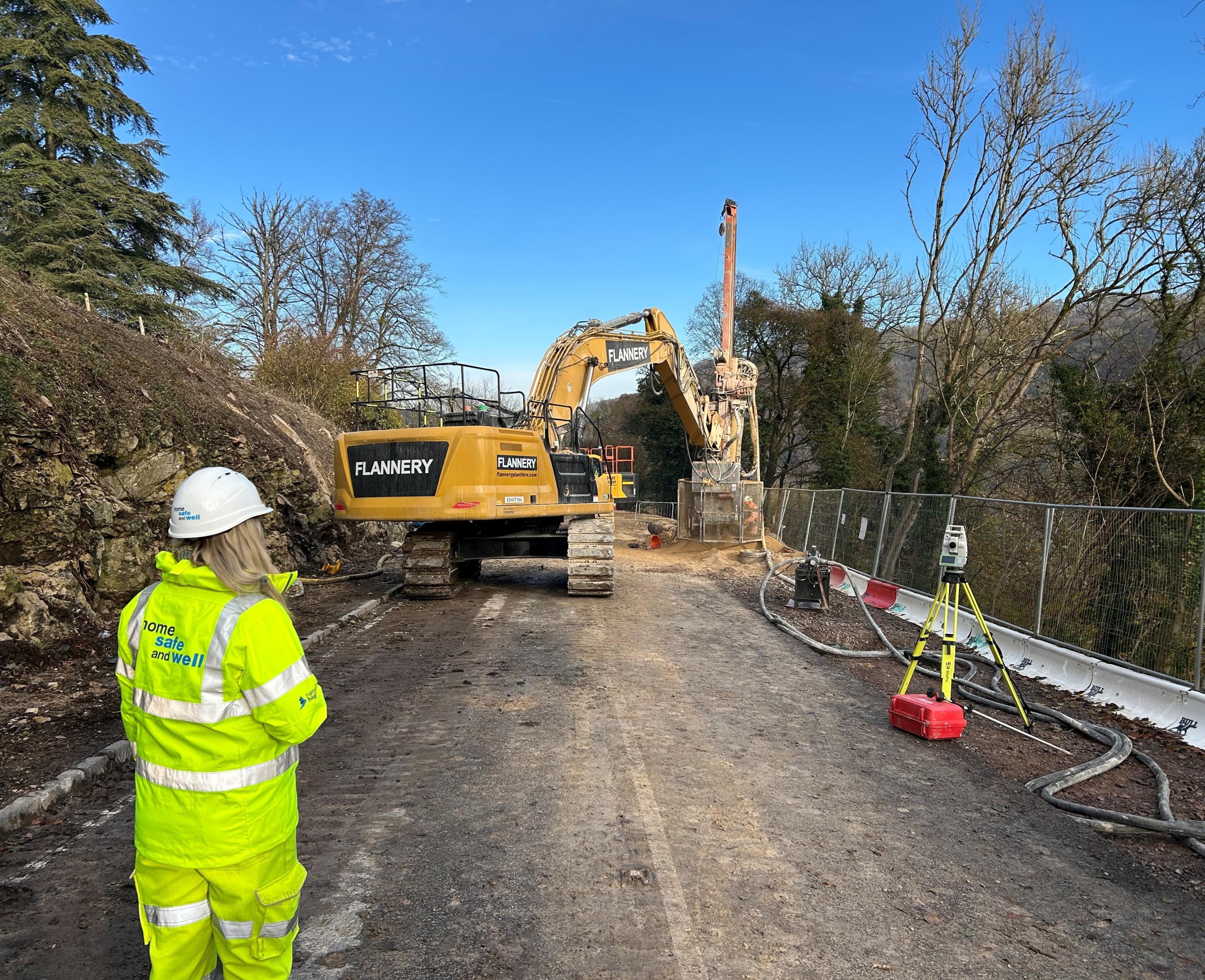 Photo shows a 35t excavator, drilling the rock sockets as part of the piling installation to support the A36 road embankment