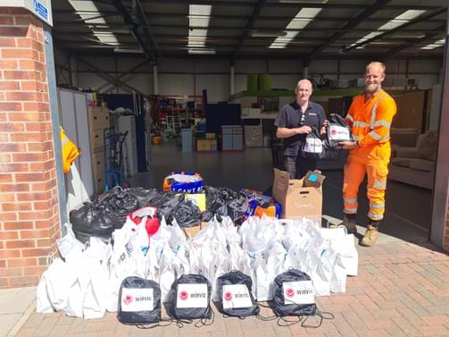 Two contractors in work wear, a collection of bags for charity