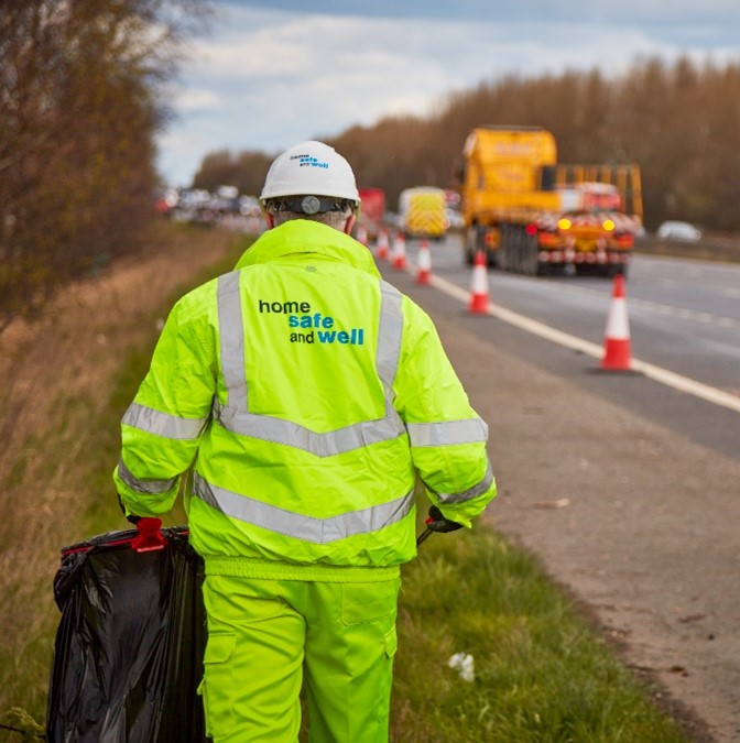 Person in hi-vis clothing picking litter from motorway verge