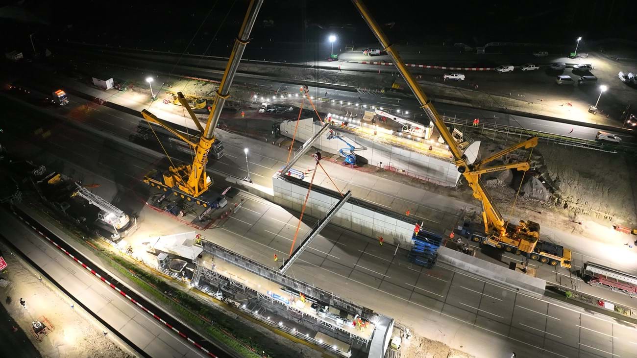 The cranes lifting the first beams into position on either side of the carriageway